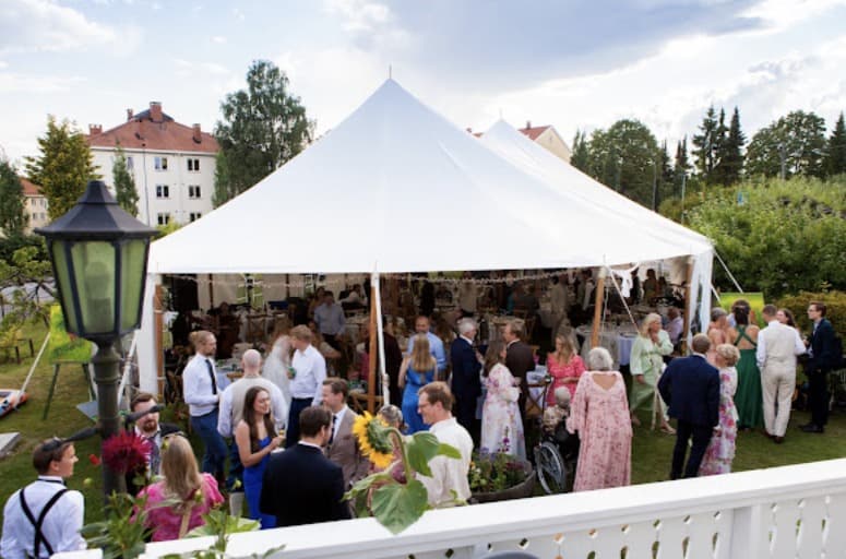 Bryllupsgjester mingler foran seilduksteltet i hagen