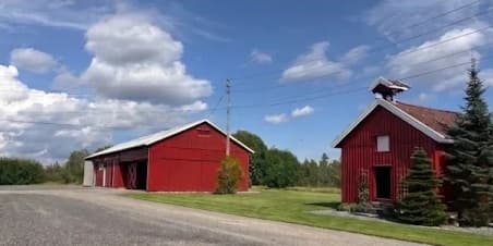 Rød låve og stabbur ved gårdsplassen på Haughem Gård